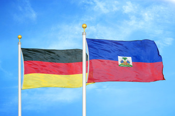 Germany and Haiti two flags on flagpoles and blue cloudy sky