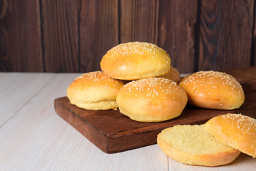 fresh delicious hamburger buns are sprinkled with sesame seeds. on a dark wooden background. close up. space for text