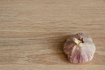 one pink winter garlic on wooden background close-up in the right corner of the frame