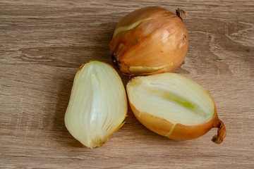 whole and cut onion on wooden background close-up