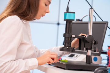 Young female designer working on a prototype device on a 3D printer