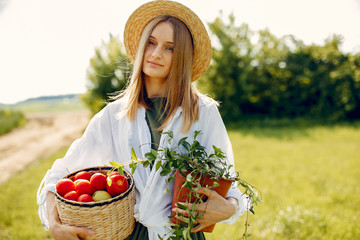 Woman gardening. Lady in a green dress. Girl with a basket of tometoes