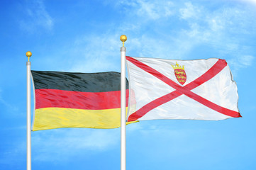 Germany and Jersey two flags on flagpoles and blue cloudy sky