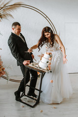 Three-tiered wedding cake falling from the table. Emotions of the bride and groom when the cake falls
