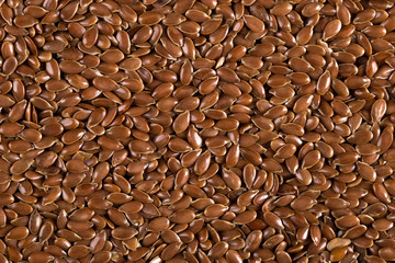 Flax grains, evenly sprinkled, brown background made of spices. Concept, copy space.