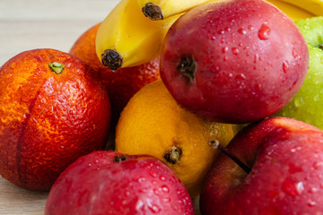 apples, bananas, lemon and oranges on a wooden table 