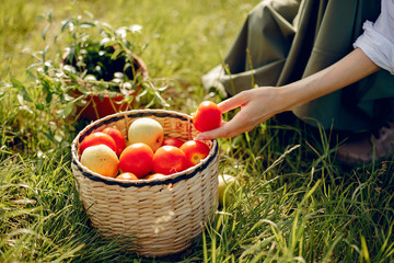 Woman gardening. Lady in a green dress. Girl with a basket of tometoes