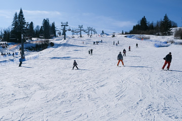 snowy ski slope full of skiers and snowboarders