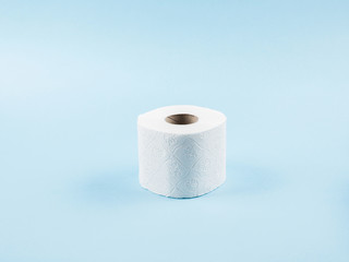 White toilet paper roll on blue abstract background. Personal hygiene supplies for restroom. Panic concept during coronavirus pandemic.