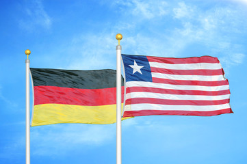 Germany and Liberia two flags on flagpoles and blue cloudy sky