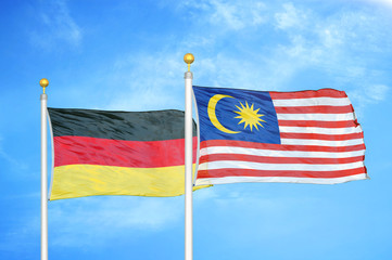 Germany and Malaysia two flags on flagpoles and blue cloudy sky