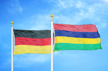 Germany and Mauritius two flags on flagpoles and blue cloudy sky