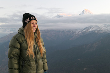 Naklejka premium Girl standing in front of the mountains. White clouds. Green forest.