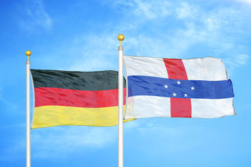 Germany and Netherlands Antilles two flags on flagpoles and blue cloudy sky