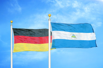 Germany and Nicaragua two flags on flagpoles and blue cloudy sky