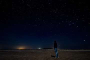 Masirah island, Oman, January 1, 2020: Gorgeous night image of a standing European man.stargazing in the middle of the desert