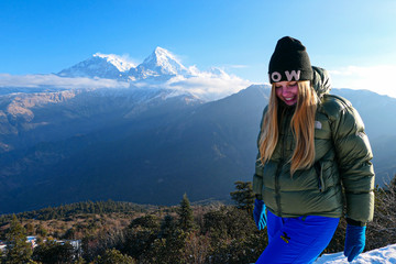Girl standing in front of the mountains. White clouds. Green forest.