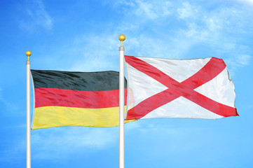 Germany and Northern Ireland two flags on flagpoles and blue cloudy sky