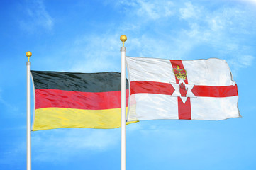 Germany and Northern Ireland two flags on flagpoles and blue cloudy sky