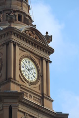 Large clock face showing two o'clock on The Sydney Town Hall building. Blue sky background. Australia