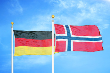 Germany and Norway two flags on flagpoles and blue cloudy sky