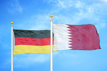 Germany and Qatar two flags on flagpoles and blue cloudy sky