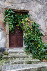 Entrance to a stone building with a wooden door decorated with greenery