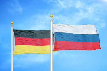 Germany and Russia two flags on flagpoles and blue cloudy sky