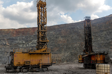 A daytime general view of an iron ore quarry. In sunny weather. A drilling machine for making holes for laying explosives. For mining, iron ore. A drill for making holes for laying explosives.