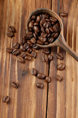 Wooden spoon with full coffee beans on a wooden table. Selective focus