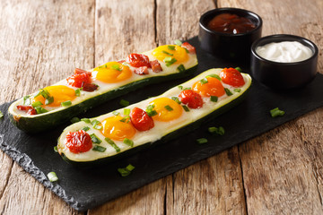 Breakfast of baked zucchini with eggs, tomatoes close-up on a slate board. horizontal