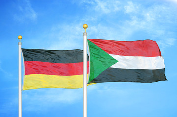 Germany and Sudan two flags on flagpoles and blue cloudy sky