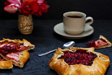 Homemade Gallet pastries with berries, berry tea, compote on a black background