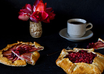 Homemade Gallet pastries with berries, berry tea, compote on a black background