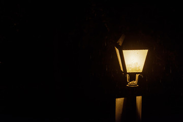 Fototapeta na wymiar Streetlight lit in the dark on a rainy night
