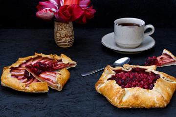 Homemade Gallet pastries with berries, berry tea, compote on a black background