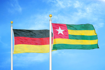 Germany and Togo two flags on flagpoles and blue cloudy sky