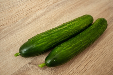 two juicy green cucumbers on a wooden table
