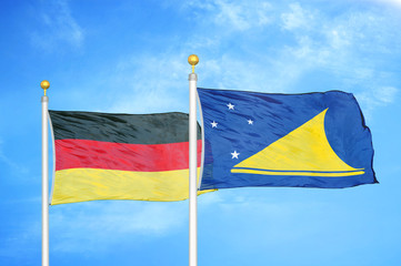 Germany and Tokelau two flags on flagpoles and blue cloudy sky