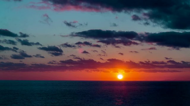 Sunset sea timelapse. Sun goes down the horizon. Nice warm colors in the sky and the clouds. Tropical summer feelings. Hot seascape. Day to dusk over the horizon.