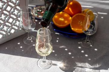 Pouring of cold fino sherry fortified wine in glass in sunlights, andalusian style interior on...