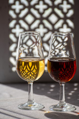 Glasses with cold dry fino and sweet cream sherry fortified wine in sunlights, andalusian style interior on background