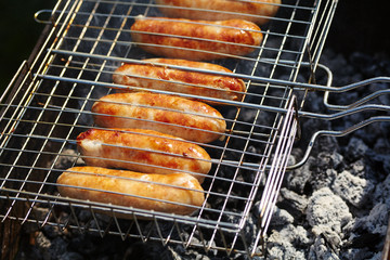 rubicund sausages are roasted on coals. Barbecue on grill in the smoke.