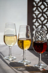 Glasses with cold dry fino and sweet cream sherry fortified wine in sunlights, andalusian style interior on background