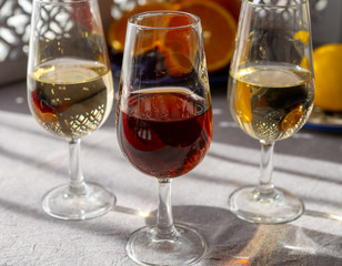 Glasses with cold dry fino and sweet cream sherry fortified wine and orange in sunlights, andalusian style interior on background