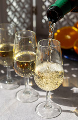 Pouring of cold fino sherry fortified wine in glass in sunlights, andalusian style interior on background
