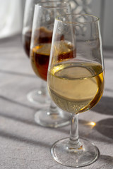 Glasses with cold dry fino and sweet cream sherry fortified wine in sunlights, andalusian style interior on background