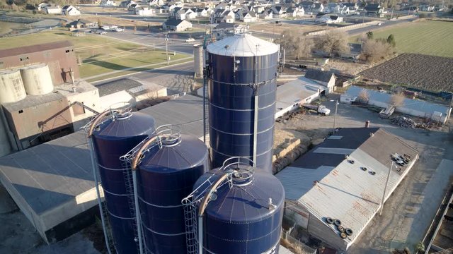 A drone partially orbits the storage silos and pens of a generational family farm capturing footage from the southeast in the late afternoon light.