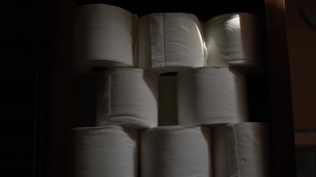 Stabilized slow zoom out shot of a stack of toilet paper in a cupboard.