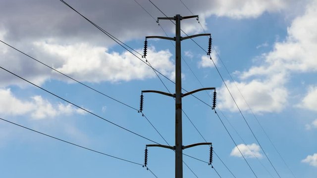 A windy day time lapse of a High Voltage Power line and clouds forming and passing behind it as is shakes and shimmies in the wind.